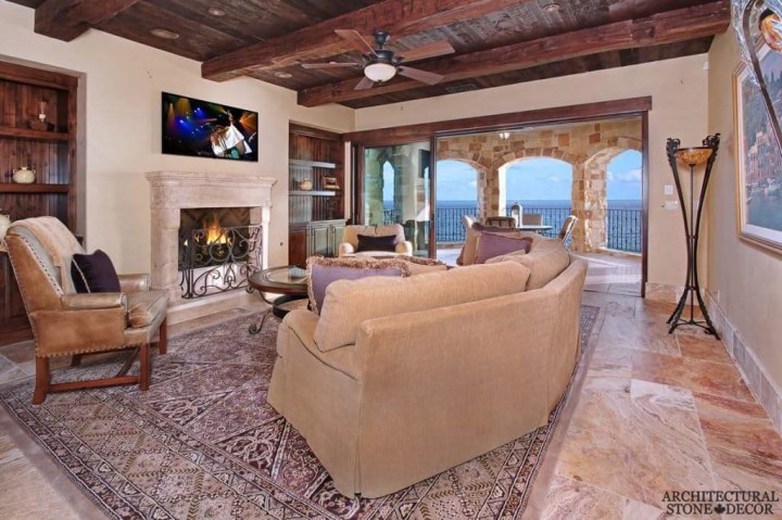 salvaged reclaimed rustic antique limestone natural stone hand carved fireplace mantel canada living room decor ceiling wood beams stone roman arches